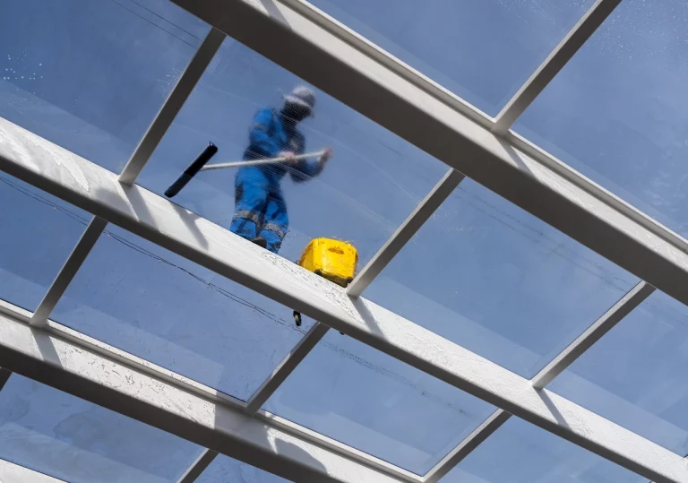 Reinigungskraft reinigt Glasdach