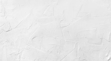 Nahaufnahme von weißem Strukturputz, der eine unregelmäßige, texturierte Oberfläche mit verschiedenen Linien und Mustern zeigt.