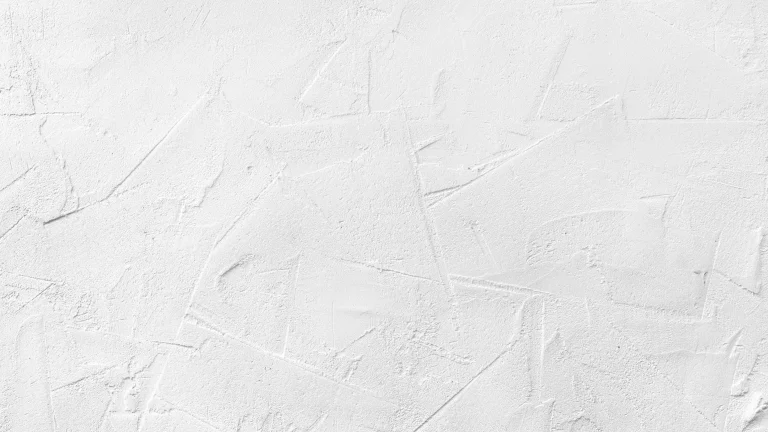 Nahaufnahme von weißem Strukturputz, der eine unregelmäßige, texturierte Oberfläche mit verschiedenen Linien und Mustern zeigt.