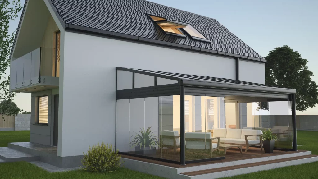 Moderne Ansicht eines Einfamilienhauses mit einem Kaltwintergarten aus Glas und Metallrahmen an der Rückseite des Gebäudes. Der Wintergarten ist mit Sitzmöbeln ausgestattet und grenzt an eine Terrasse.