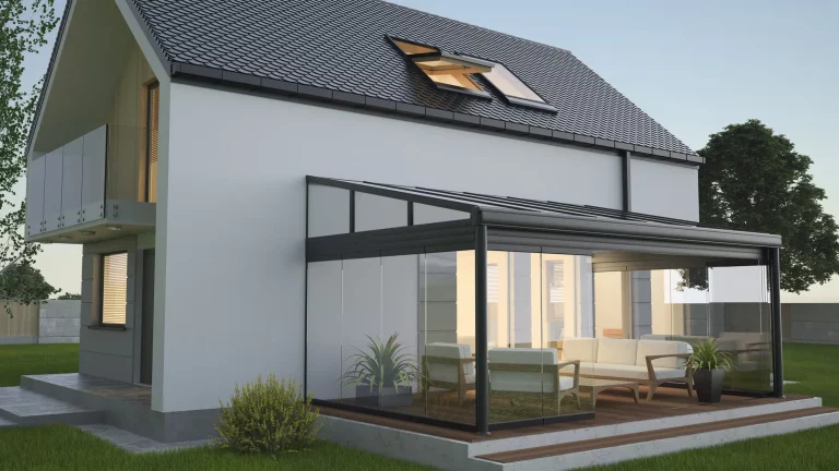 Moderne Ansicht eines Einfamilienhauses mit einem Kaltwintergarten aus Glas und Metallrahmen an der Rückseite des Gebäudes. Der Wintergarten ist mit Sitzmöbeln ausgestattet und grenzt an eine Terrasse.