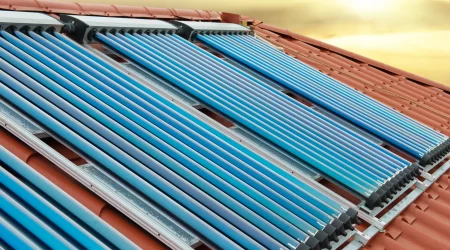 Solarkollektoren mit Vakuumröhren auf einem Ziegeldach, bei Sonnenuntergang