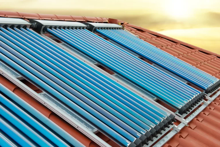 Solarkollektoren mit Vakuumröhren auf einem Ziegeldach, bei Sonnenuntergang
