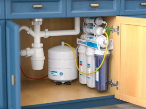 Unter einem Waschbecken installierte Wasserenthärtungsanlage mit mehreren Filtern und einem Wassertank zur Reduzierung von Wasserhärte und zur Verbesserung der Wasserqualität in Haushalten