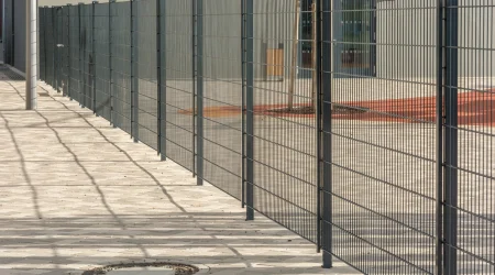 Zaun der ein Grundstück begrenzt und schatten auf das Pflaster wirft