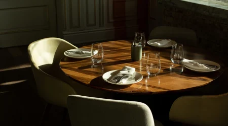 Gedeckter Esstisch aus Holz in der Sonne.