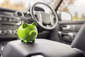 grünes Sparschwein steht im Inneren eines Autos.