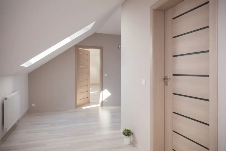 Heller Raum mit zwei modernen Innentüren aus Holz. Die vordere Tür hat horizontale Glasstreifen, während die hintere Tür offen steht und in ein weiteres Zimmer führt. Die Türen sind aus hellem Holz gefertigt und fügen sich in das minimalistische Design des Raumes ein.