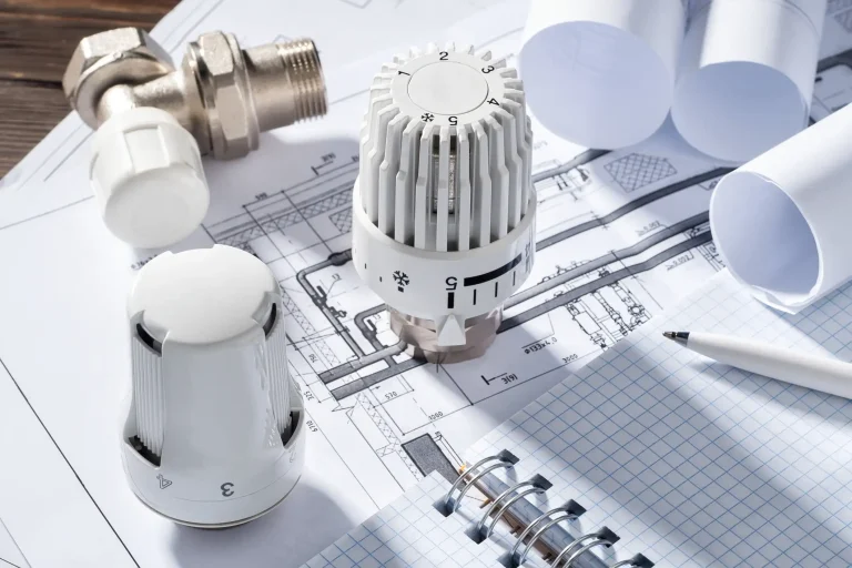 Planungsdokumente zur Heizlastberechnung mit Thermostatventilen, Skizzen und technischen Zeichnungen. Verschiedene Thermostatköpfe und ein Kugelventil auf einem technischen Bauplan.