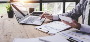 Mann tippt auf Laptop und Taschenrechner, vor ihm