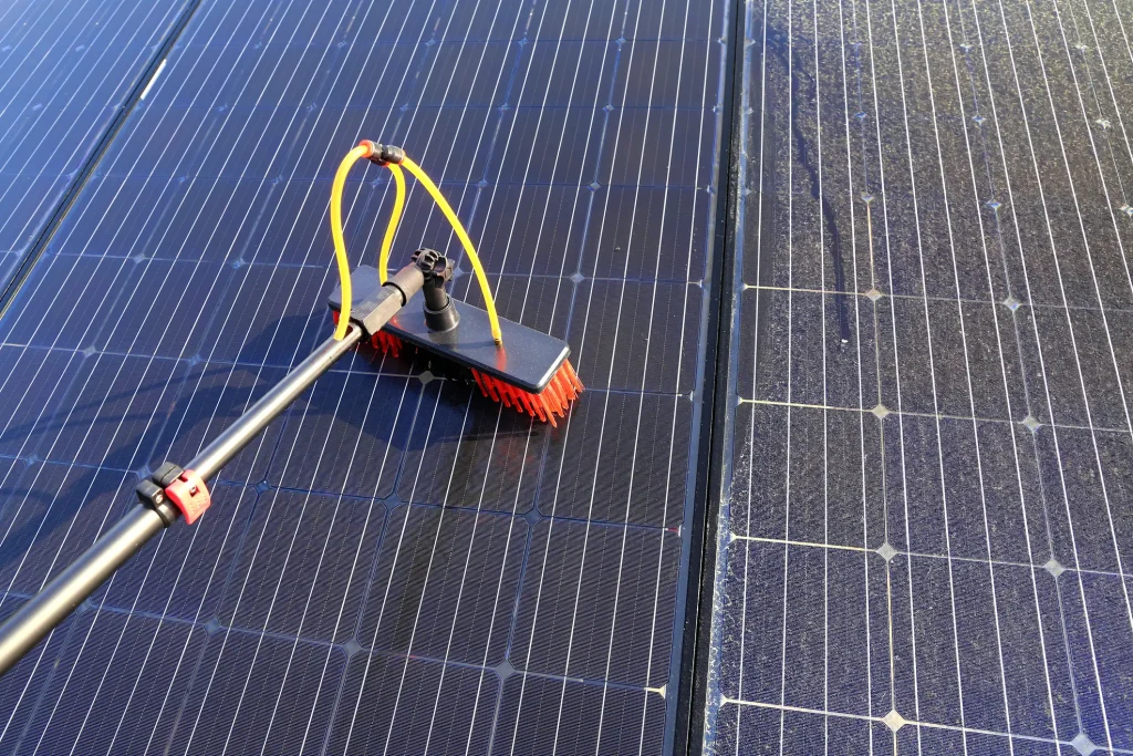 Reinigung von Solarmodulen mit einer speziellen Bürste und Wasserschlauch.
