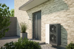 Wärmepumpe neben einem Hauseingang an einer Hausfassade aus hellen Ziegeln.