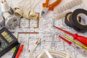 Werkzeug und Materielaien eines Elektriker liegen auf einem Bauplan.