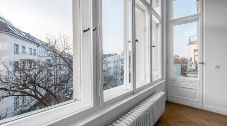 Fensterfront mit weißen Fensterrahmen und Blick auf Reihenhäuser