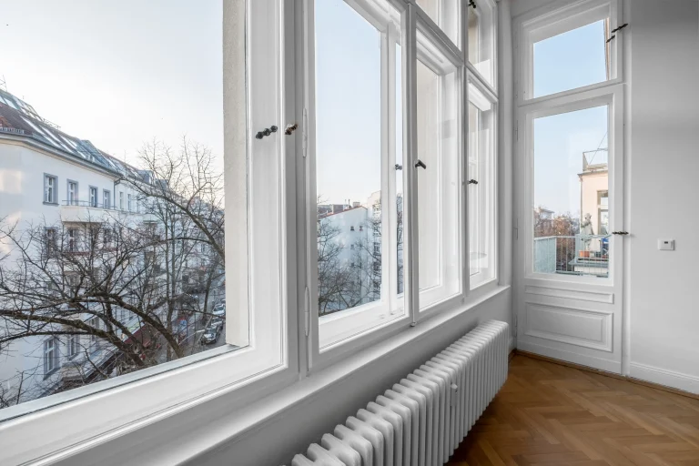 Fensterfront mit weißen Fensterrahmen und Blick auf Reihenhäuser