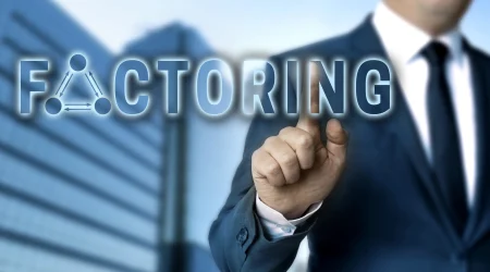 Ein Geschäftsmann in Anzug und Krawatte steht vor einem modernen Bürogebäude. Er zeigt mit seinem Finger auf das Wort ‚Factoring‘, das in großen, leuchtenden Buchstaben auf dem Bild dargestellt ist.
