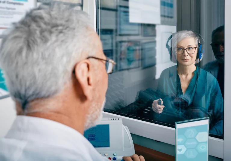 Hörakustiker mach mit einer älteren Patientin einen Hörtest.