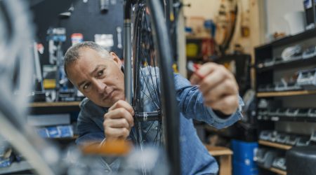 Fahrradmechaniker prüft die Unwucht eines Fahrradreifens.