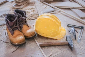 Sicherheitsschuhe und ein Sicherheitshelm liegen auf dem Boden einer Baustelle.