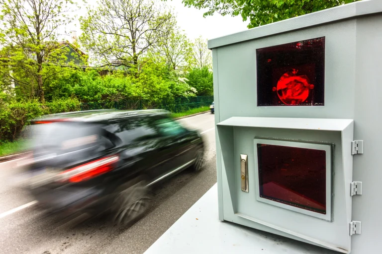 Auto fährt mit erhöhter Geschwindigkeit an einem Blitzer vorbei der auslöst.