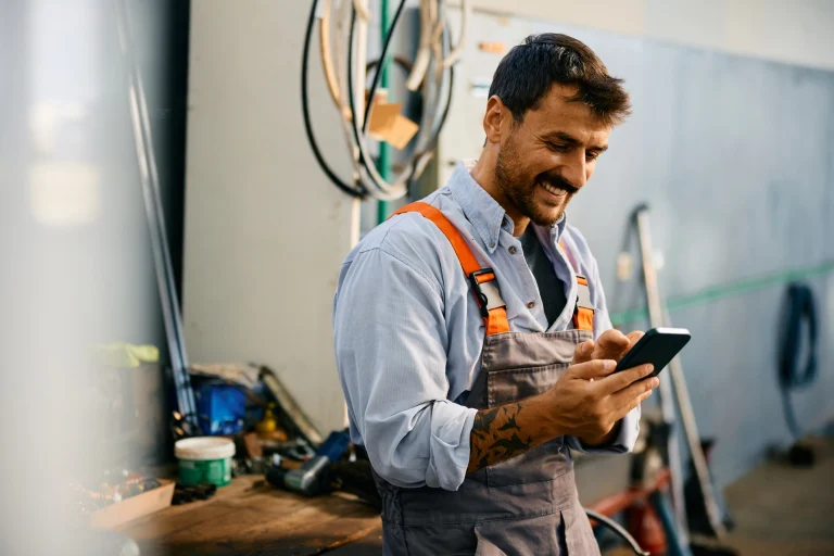 Handwerker tippt auf seinem Handy, um eine seine App zu öffnen.