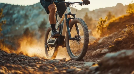 Ein Mann fährt auf einem E-Mountain Bike einen Berg herunter, auf dem viel Geröll herumliegt.