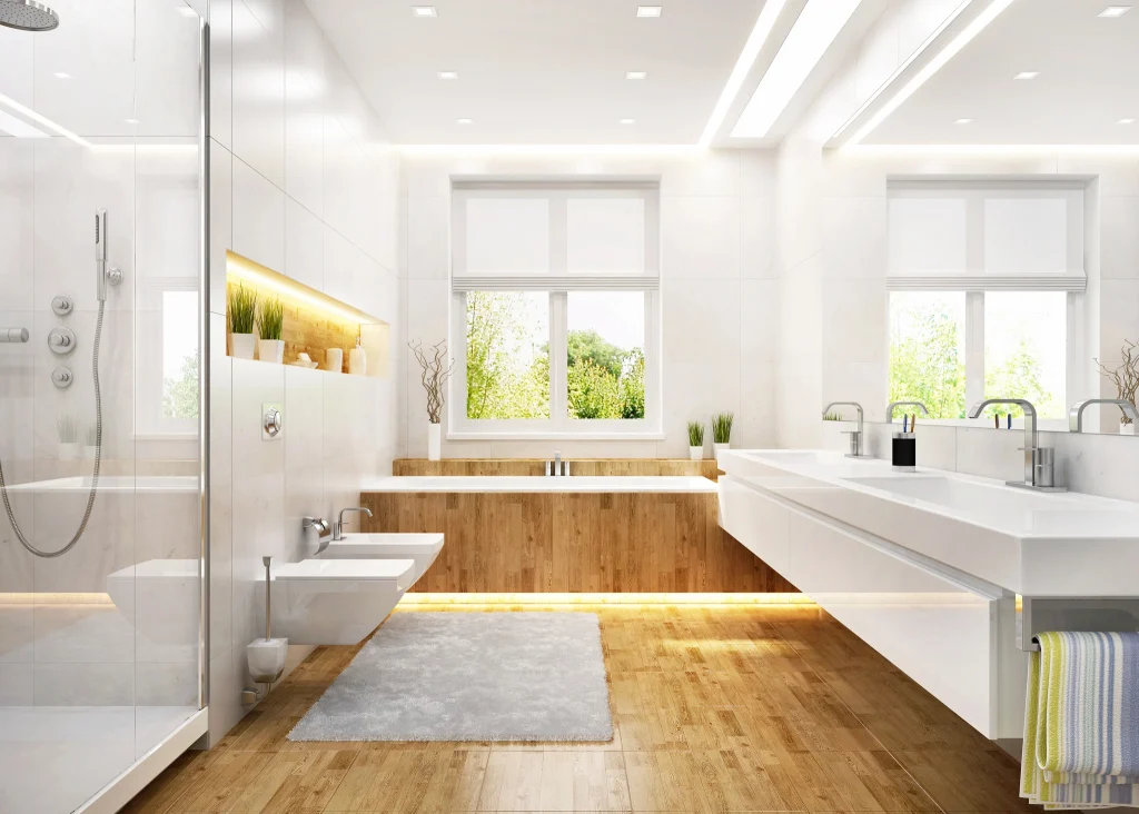 Modernes, helles Badezimmer mit Holz- und Marmorelementen. Eine großzügige Dusche mit Glaswand, eine freistehende Badewanne mit Holzverkleidung und ein Doppelwaschbecken mit modernen Armaturen. Das Design wird durch indirekte Beleuchtung, ein großes Fenster mit Blick ins Grüne und stilvolle Dekorationselemente ergänzt. Ein flauschiger Teppich auf dem Holzfußboden sorgt für Gemütlichkeit.