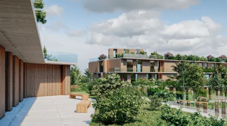 Moderne Wohnanlage mit flachen, begrünten Dächern, Holzfassaden und großen Fensterfronten, eingebettet in eine parkähnliche Landschaft mit Sitzbereichen und Spielgeräten unter freiem Himmel.