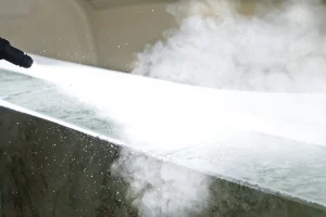 Industrielle CO₂-Schneestrahl-Reinigung: Eine Düse sprüht unter hohem Druck Trockeneispartikel auf eine Oberfläche, wobei Schmutz und Verunreinigungen kontaktlos entfernt werden.