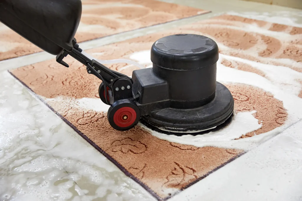 Nahaufnahme einer Einscheibenmaschine bei der Reinigung eines Teppichs mit Schaum in einer Teppichreinigungsanlage.