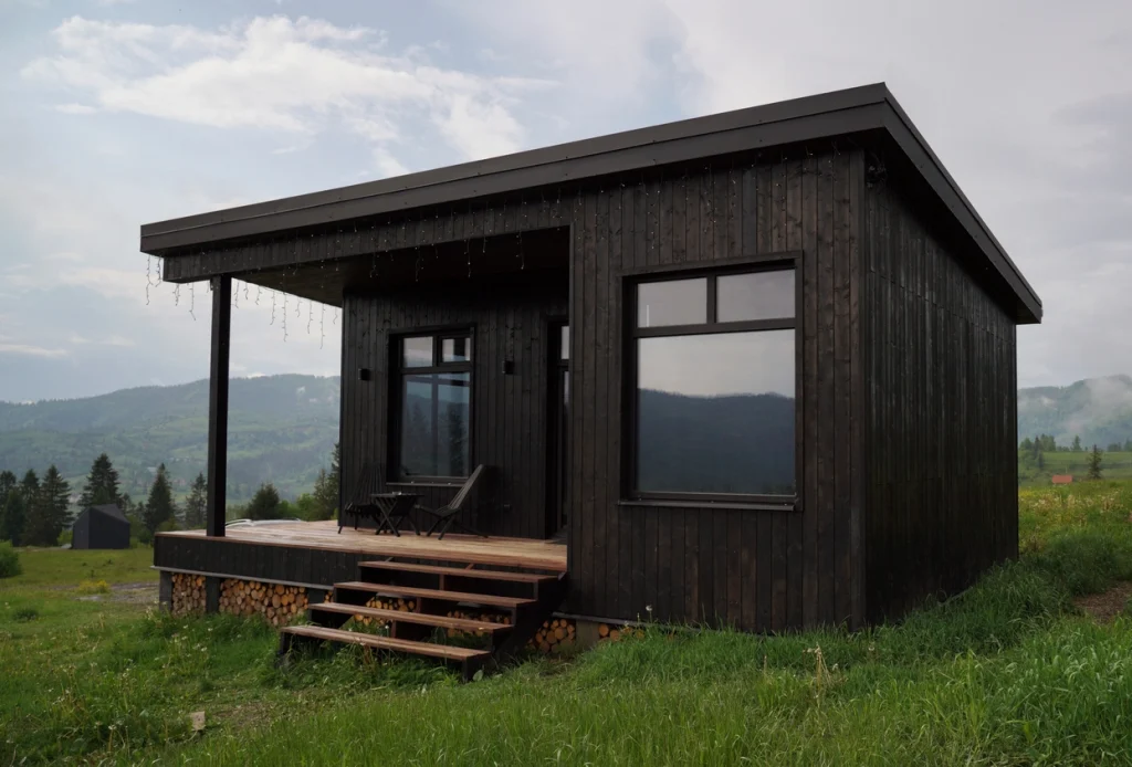Schwarzes stationäres Tiny House in einem alpinen Umfeld