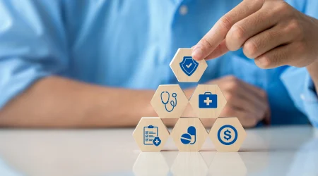 Eine Pyramide aus Holzklötzen wird symbolisch für die Leistungen einer Krankenkasse gestapelt. Auf den Holzklötzen sind kleine Gesundheissymbole zu sehen.
