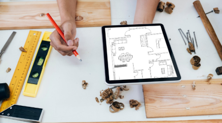 Heizungsmonteur hält einen Grundriss digital auf einem Tablet in der Hand.