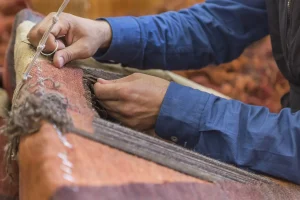 Reparatur in Handarbeit an einem traditionellen Teppich mit Nadel und Faden in einem Webrahmen.