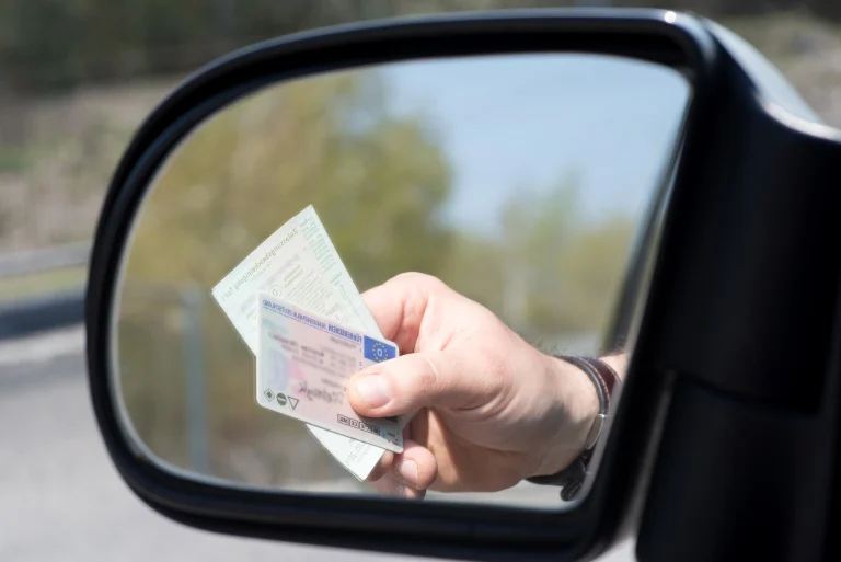 Seitenspiegel eines Autos bei einer Verkehrskontrolle mit Führerschein und Fahrzeugpapieren