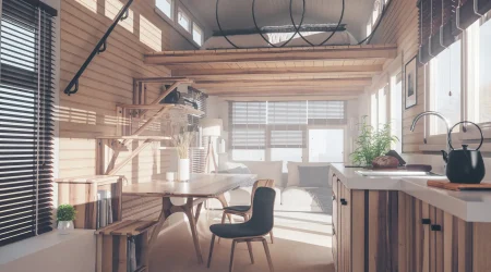 Inneneinrichtung eines Tiny House mit viel Holz, offener Küche, Esstisch, gemütlichem Wohnbereich und Schlafplatz auf einer erhöhten Galerie.