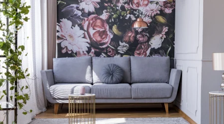 Fototapete an einer Wand eines Wohnzimmers. Vor der Wand steht ein graues Sofa. Darüber hängen zwei Pendelleuchten in Kupferoptik.
