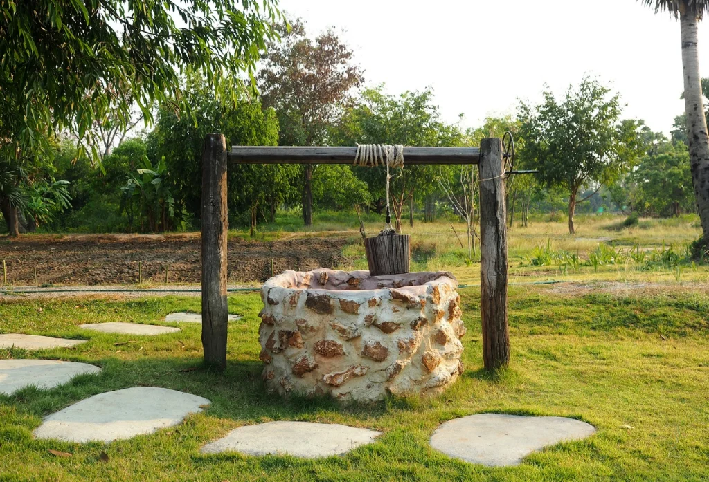 Alte ländliche Wasserstelle aus Stein mit Metallhahn in natürlicher Umgebung, rustikaler Brunnen auf dem Land