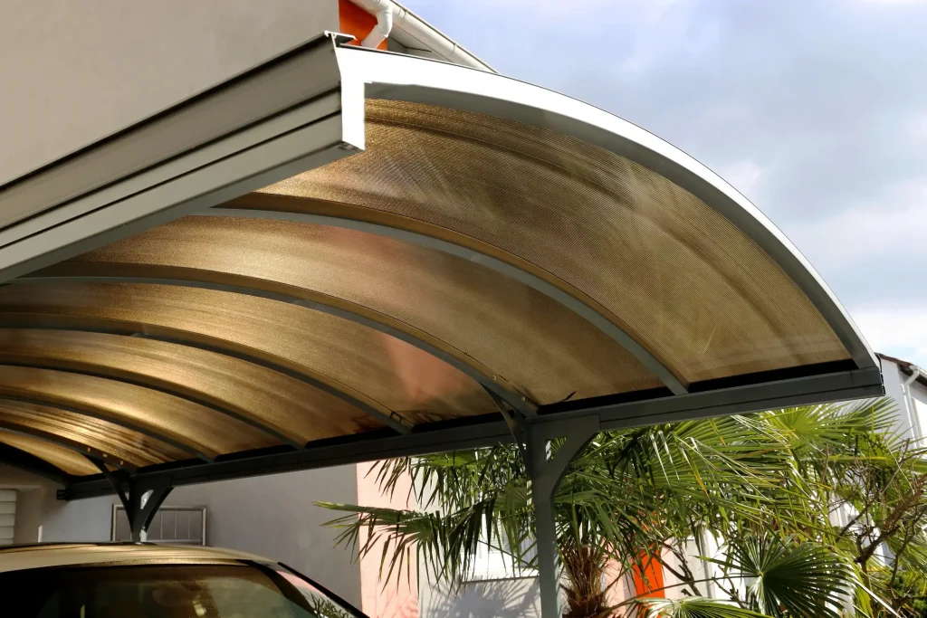 Gebogenes Carportdach aus getönten Stegplatten mit pulverbeschichteter Metallkonstruktion.