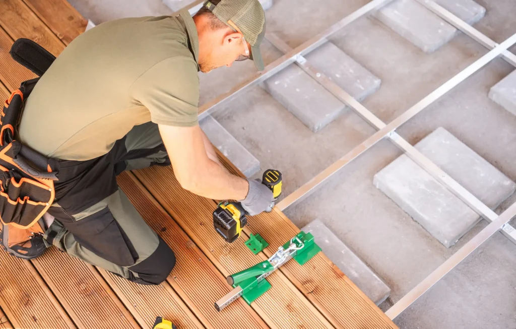 Terrassenbauer schraubt Terrassendielen aus Holz auf eine Metallunterkonstruktion.