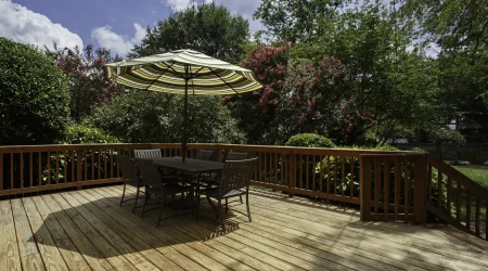 Holzterrasse im Garten mit Sitzgruppe und Sonnenschirm.