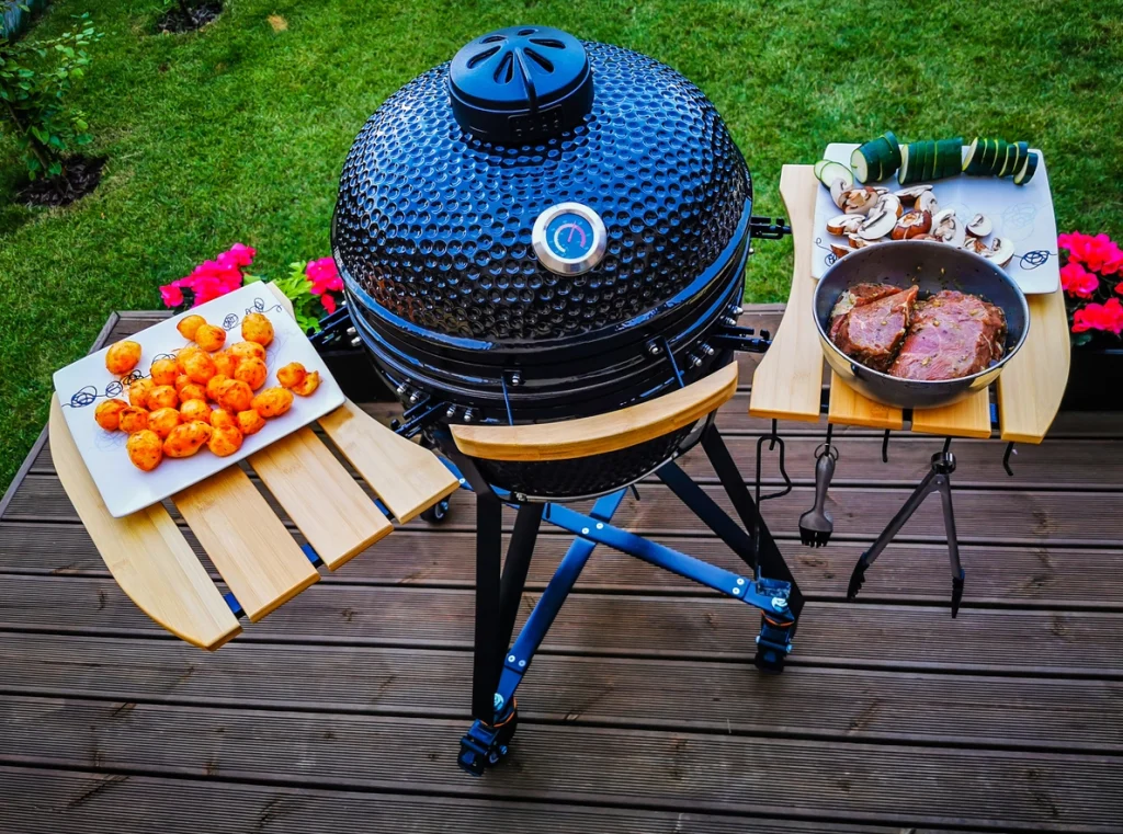 Kamado-Keramikgrill mit Rindersteaks und Gemüse auf dem Grillrost, Grillen im Freien