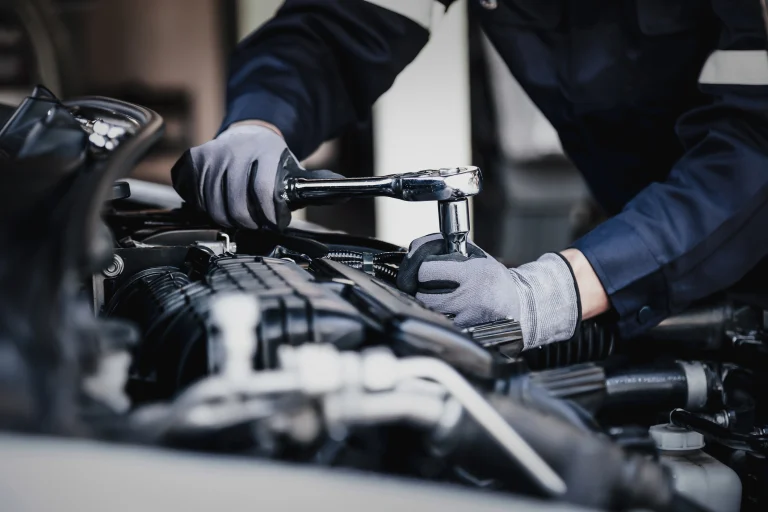 Mechaniker verschraubt wieder alle Teile nach einer Reparatur am Motor im Auto.