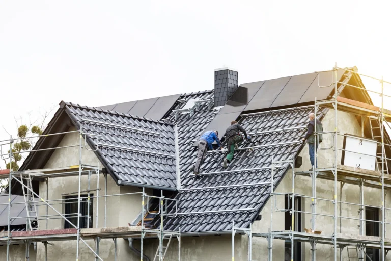 Arbeiter montieren Solarkollektoren auf dem Dach eines Einfamilienhauses zur Nutzung von Solarenergie