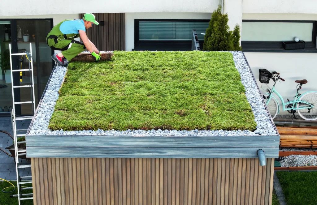 Fachgerechte Installation eines extensiven Gründachs auf einem Carport mit einer Person, die die Vegetationsmatten auslegt.