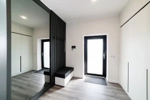 Heller moderner Flur mit dunklen Gestaltungselementen und einem großen Ganzkörperspiegel an der Wand.