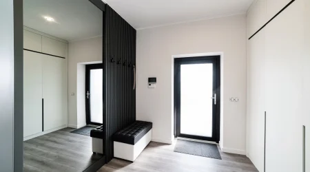 Heller moderner Flur mit dunklen Gestaltungselementen und einem großen Ganzkörperspiegel an der Wand.