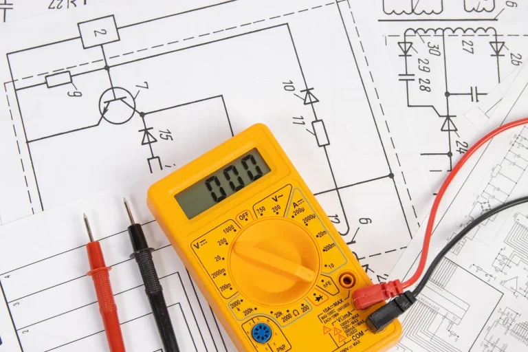 Digitales Multimeter mit Messleitungen auf technischen Schaltplänen für Elektrotechnik und Elektronik.