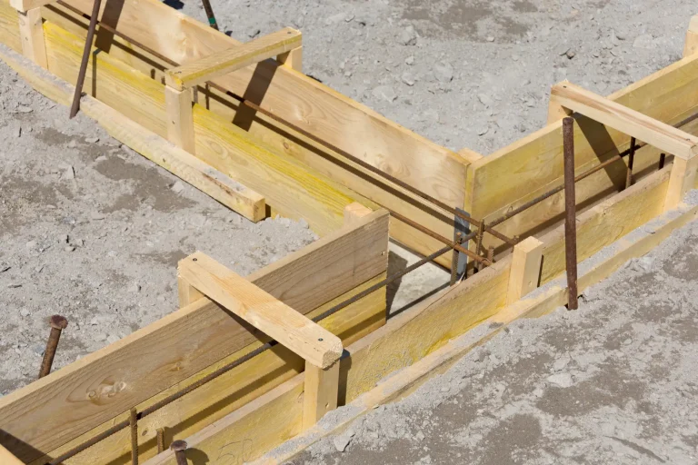 Holzschalung mit eingelegter Bewehrung für ein Streifenfundament, vorbereitet als stabile Grundlage für den Bau eines Carports.