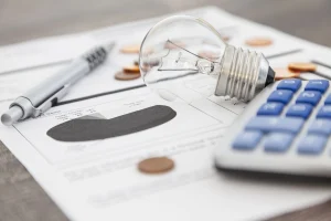 Eine Glühbirne liegt auf einem Dokument, dass die aktuellen Strompreise systematisch miteinander vergleicht.